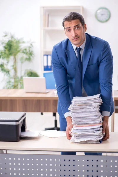 Jonge mannelijke werknemer maakt kopieën bij kopieermachine — Stockfoto