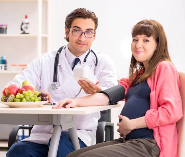 Беременная женщина посещает врача, обсуждая здоровую диету — стоковое фото
