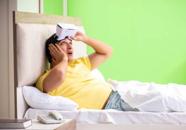 Yatak odasında sanal gözlüklü genç adam.
