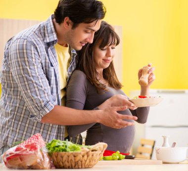 Erkek ve hamile kadın mutfakta salata hazırlıyorlar.