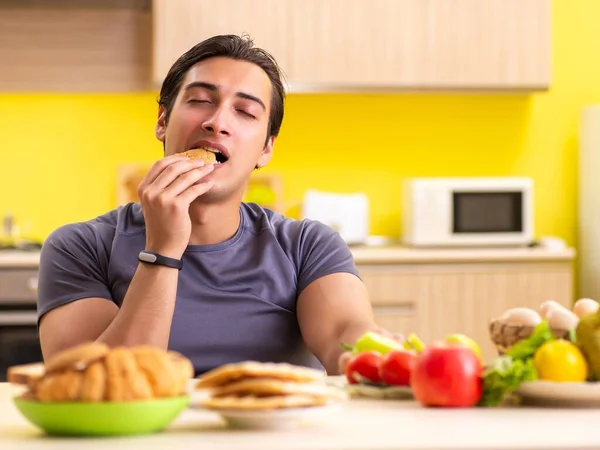 健康的で不健康な食べ物を選ぶのが難しい男 — ストック写真