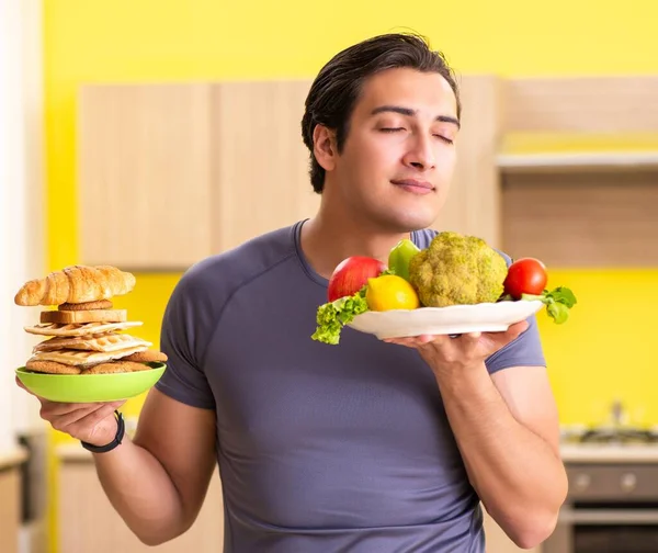 Homme ayant le choix difficile entre une alimentation saine et malsaine — Photo