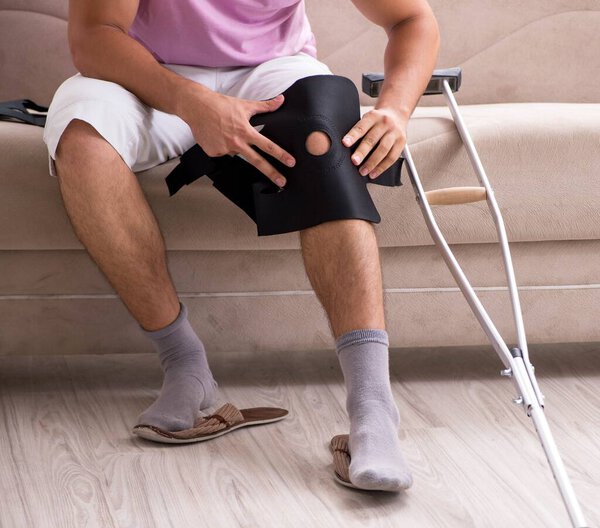 Раненый мужчина, выздоравливающий дома после спортивной травмы
