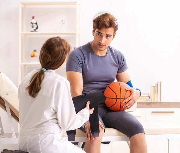 Guapo jugador de baloncesto visitando médico traumatólogo femenino — Foto de Stock