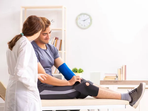 Jovem paciente do sexo masculino visitando médico traumatologista feminino — Fotografia de Stock