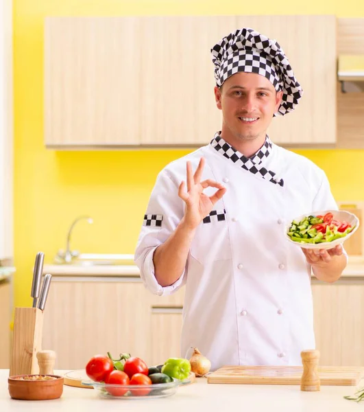 Jovem cozinheiro profissional preparando salada na cozinha — Fotografia de Stock