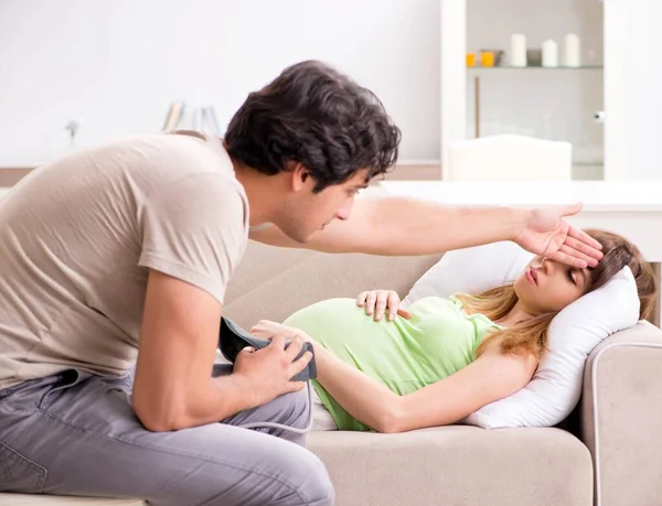 妊娠中の妻の血圧を調べる夫 — ストック写真