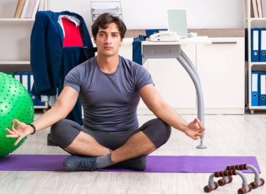 Ofiste egzersiz yapan genç bir erkek.