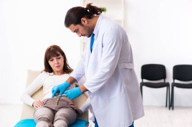 Yaralı genç kadın genç erkek doktoru ziyaret ediyor.