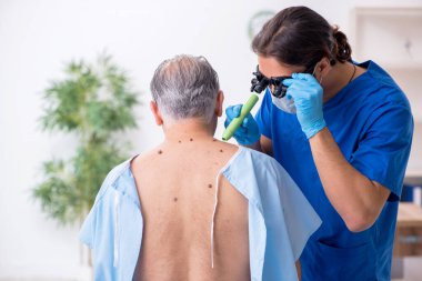 Yaşlı adam genç erkek doktor dermatoloğu ziyaret ediyor.
