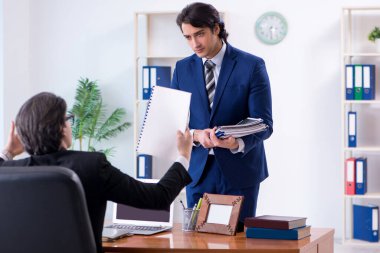 Patron ve erkek asistanı ofiste çalışıyor.