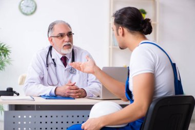 Genç erkek müteahhit yaşlı doktoru ziyaret ediyor.