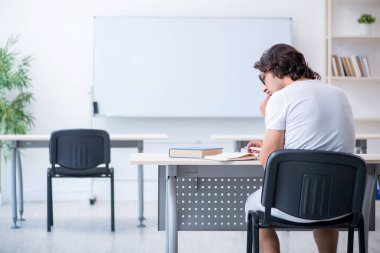 Beyaz tahtanın önünde genç bir erkek öğrenci.