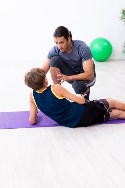 Genç baba ve oğlu egzersiz yapıyor.