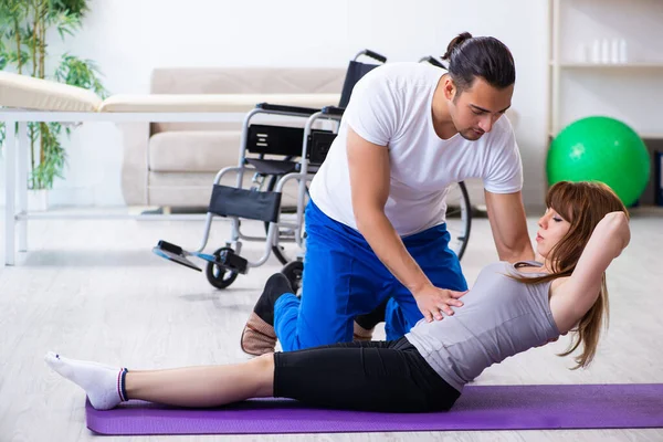 Чоловік фізіотерапевт робить вправи з травмованою жінкою на підлозі — стокове фото
