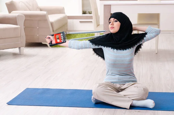 Mujer joven en hiyab haciendo ejercicios en casa —  Fotos de Stock