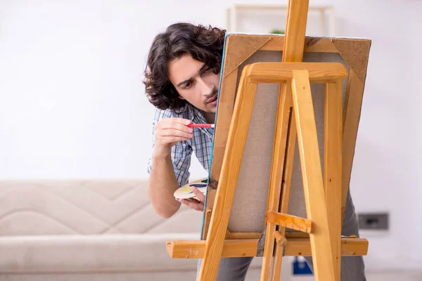 Jovem homem bonito curtindo pintura em casa — Fotografia de Stock