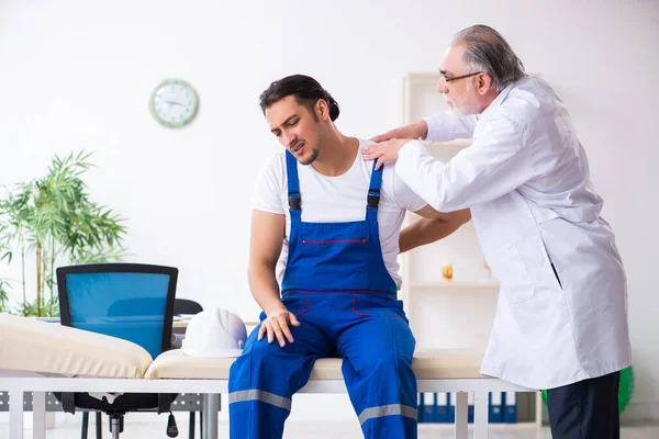 Jovem empreiteiro visitando médico velho — Fotografia de Stock