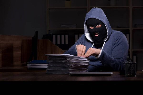 Male thief in balaclava in the office night time