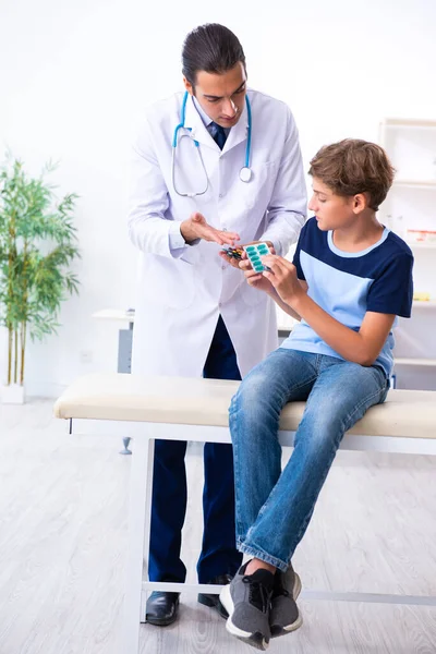 Joven médico examinando a un niño en la clínica —  Fotos de Stock