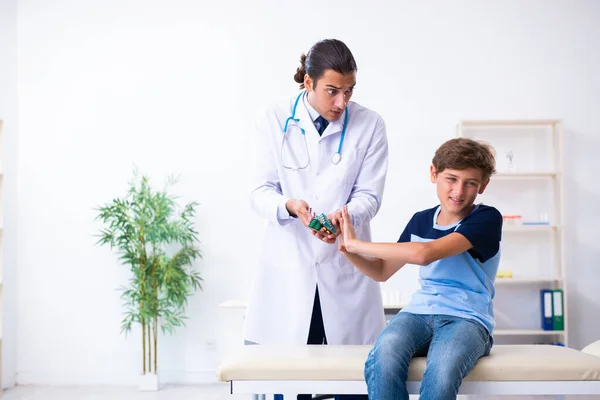 Genç erkek doktor klinikteki çocuğu muayene ediyor. — Stok fotoğraf