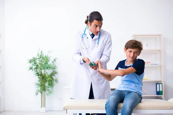 Jovem médico examinando menino na clínica — Fotografia de Stock