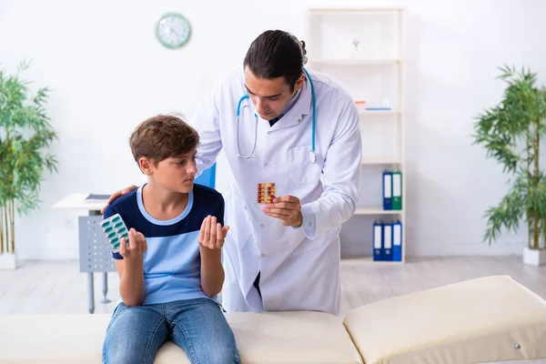 Joven médico examinando a un niño en la clínica —  Fotos de Stock