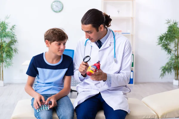 Giovane medico maschio esaminando ragazzo in clinica — Foto Stock