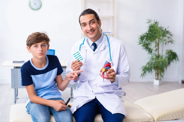 Giovane medico maschio esaminando ragazzo in clinica — Foto Stock