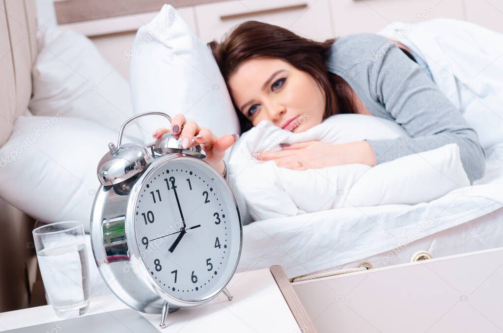 Young woman lying on the bed in time management concept