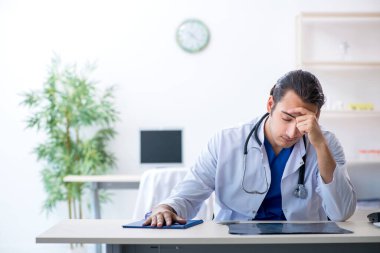 Klinikte çalışan genç erkek doktor.