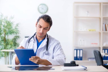 Klinikte çalışan genç erkek doktor.