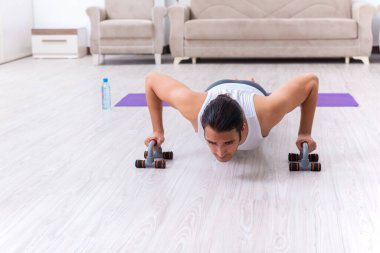 Genç adam evde antrenman ve egzersiz yapıyor.