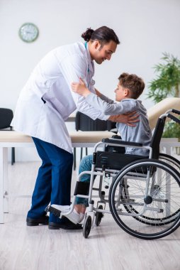 Genç erkek doktor pediatrist ve tekerlekli sandalyedeki çocuk.