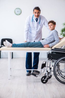 Genç erkek doktor pediatrist ve tekerlekli sandalyedeki çocuk.