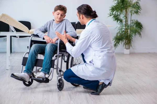 Jonge mannelijke arts kinderarts en jongen in rolstoel — Stockfoto