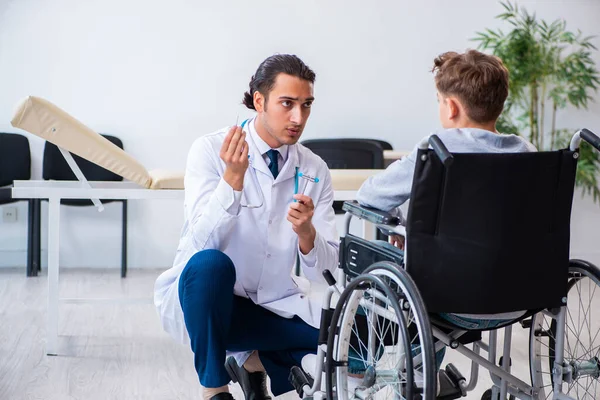 Joven doctor pediatra y niño en silla de ruedas — Foto de Stock