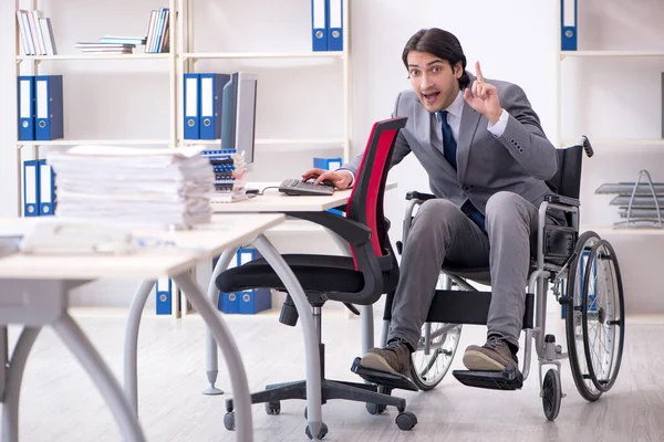 Ofiste çalışan tekerlekli sandalyedeki genç yakışıklı eleman. — Stok fotoğraf