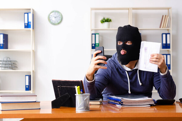 Male thief in balaclava in the office