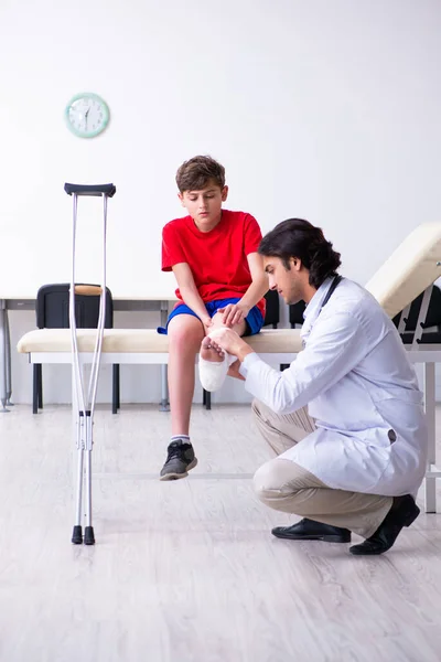 Láb sérült fiú látogató fiatal orvos traumatológus — Stock Fotó