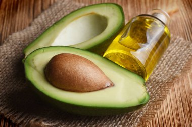 Ahşap arka plan üzerinde çul üzerine şişe yarıya taze olgun avokado 