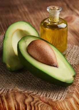 Ahşap arka plan üzerinde çul üzerine şişe yarıya taze olgun avokado 