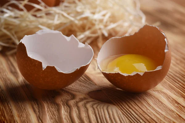 View of broken egg with fresh yolk on wooden background