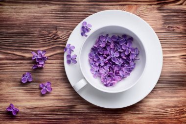 Beyaz Kupası ahşap masaya güzel Lila çiçek dolu