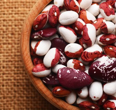 Çuval bezi arka planında tahtadan kasede fasulyeler.