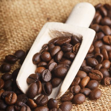 Çuval bezinde ahşap kepçeyle kavrulmuş kahve çekirdekleri.