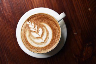 Beyaz bardakta servis edilen kahve, ahşap masa arkaplanlı.