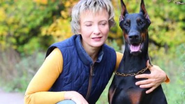 Kadın onun doberman sonbahar ormandaki okşadı