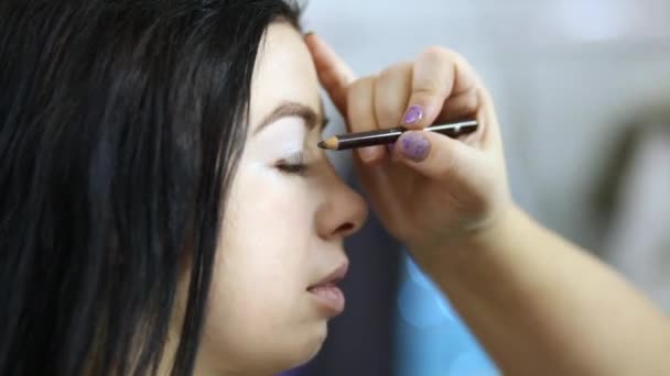 Visagiste наносит макияж карандашом на верхнее веко модели — стоковое видео