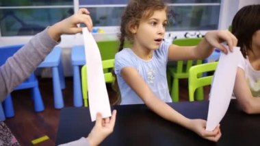 Kız dikkatle dinler ve bir parça kağıt kıvrımlar